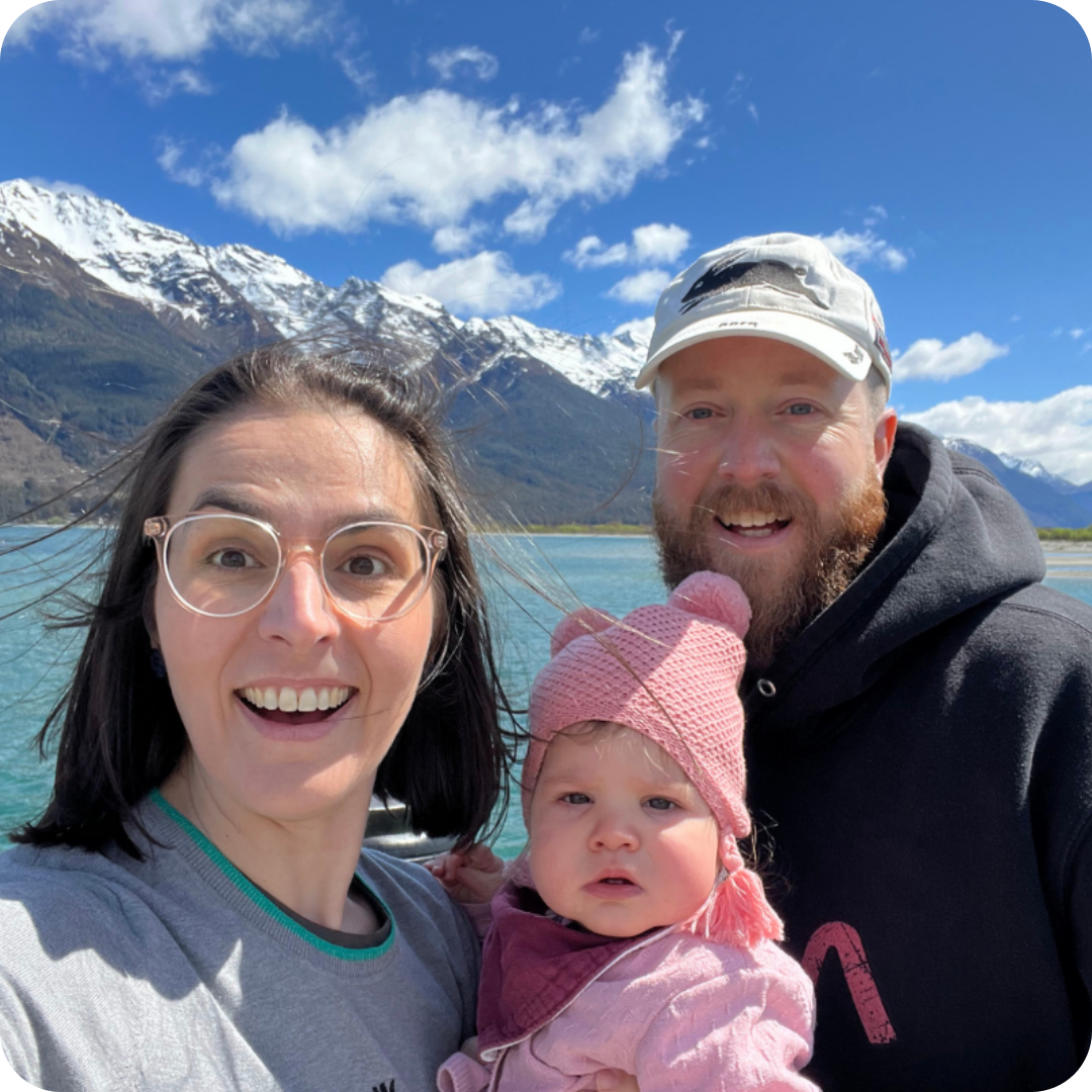 A portrait of Dean with his partner and young child taken in front of snow capped mountains.